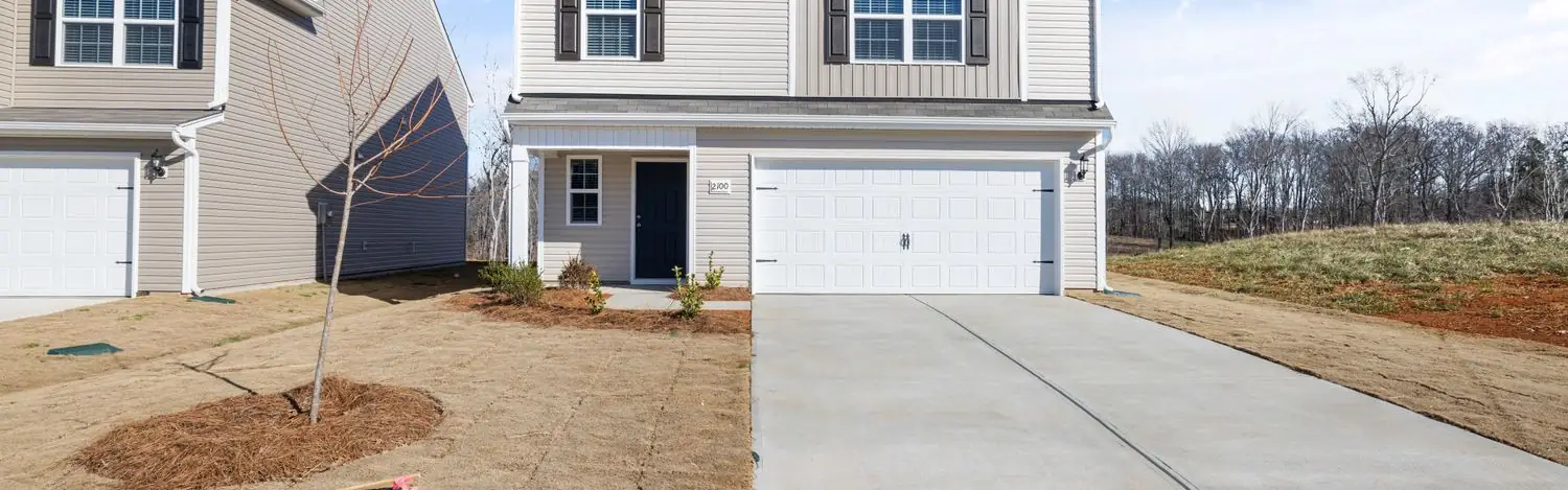 New concrete driveway leading to a white garage door on a two-story house